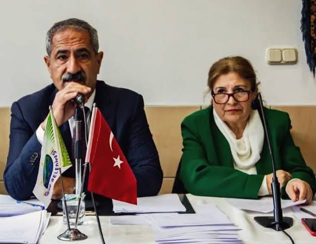 GOVDE 1 - Ali Ercan Akpolat mikrofonda, yaninda Medine Pamuk (yesil ceket), meclis masasi, Turk bayragi; temiz, 630x487.
