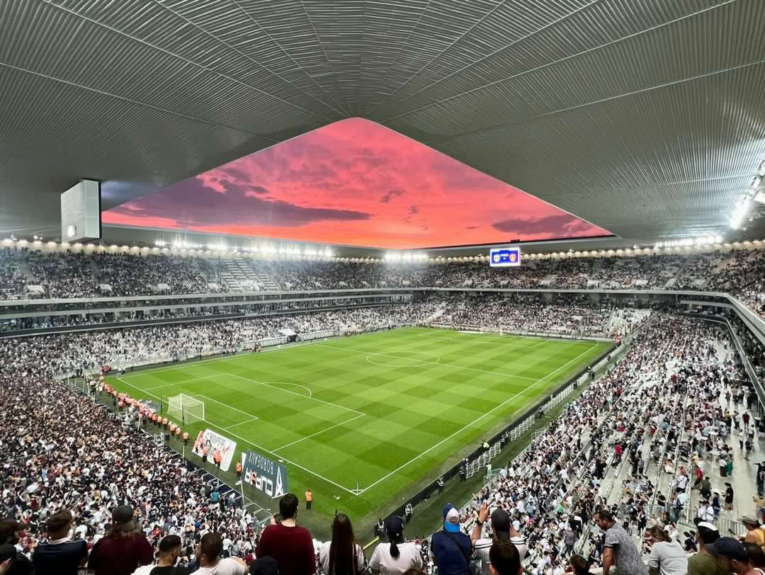 Bordeaux'nun Matmut Atlantique stadı içi, dolu tribünler ve çim saha, gün batımı gökyüzü (1080x811, temiz saha fotoğrafı)