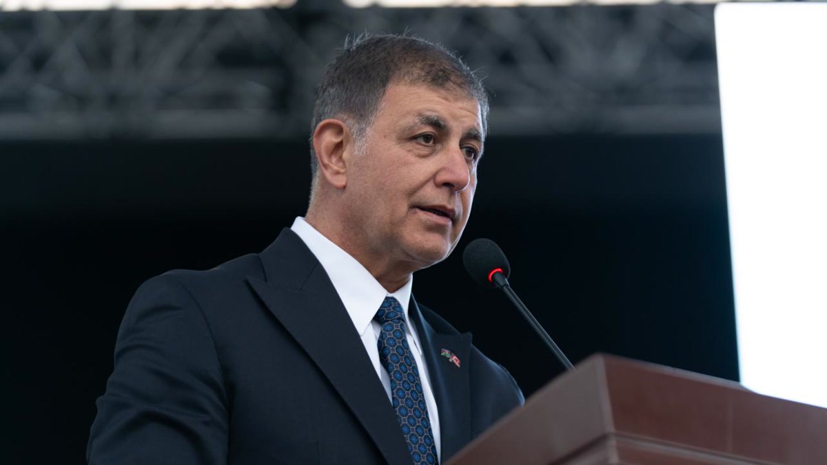 Cemil Tugay'ın kürsüde mikrofon başında konuştuğu yakın plan portre; olay karesi değil arşiv/etkinlik görüntüsü, gövdeye uygun yedek (1280x720)
