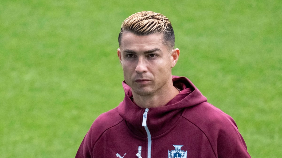 Ronaldo, Portekiz Federasyonu armalı bordo kapüşonlu üstle çim zeminde, ciddi ifade; temiz portre, 3000x1687