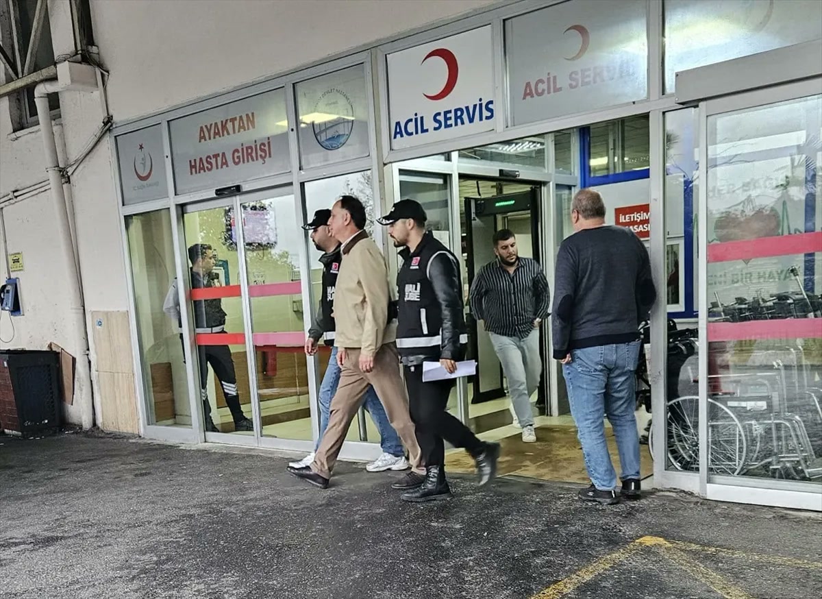 MHK soruşturması kapsamında gözaltı sonrası polis eşliğinde hastane acil servis girişinde yürüyen bir şüpheli; kimliği haberde belirtilmemiş, metinde kişiye atfedilmemeli (1200x873)