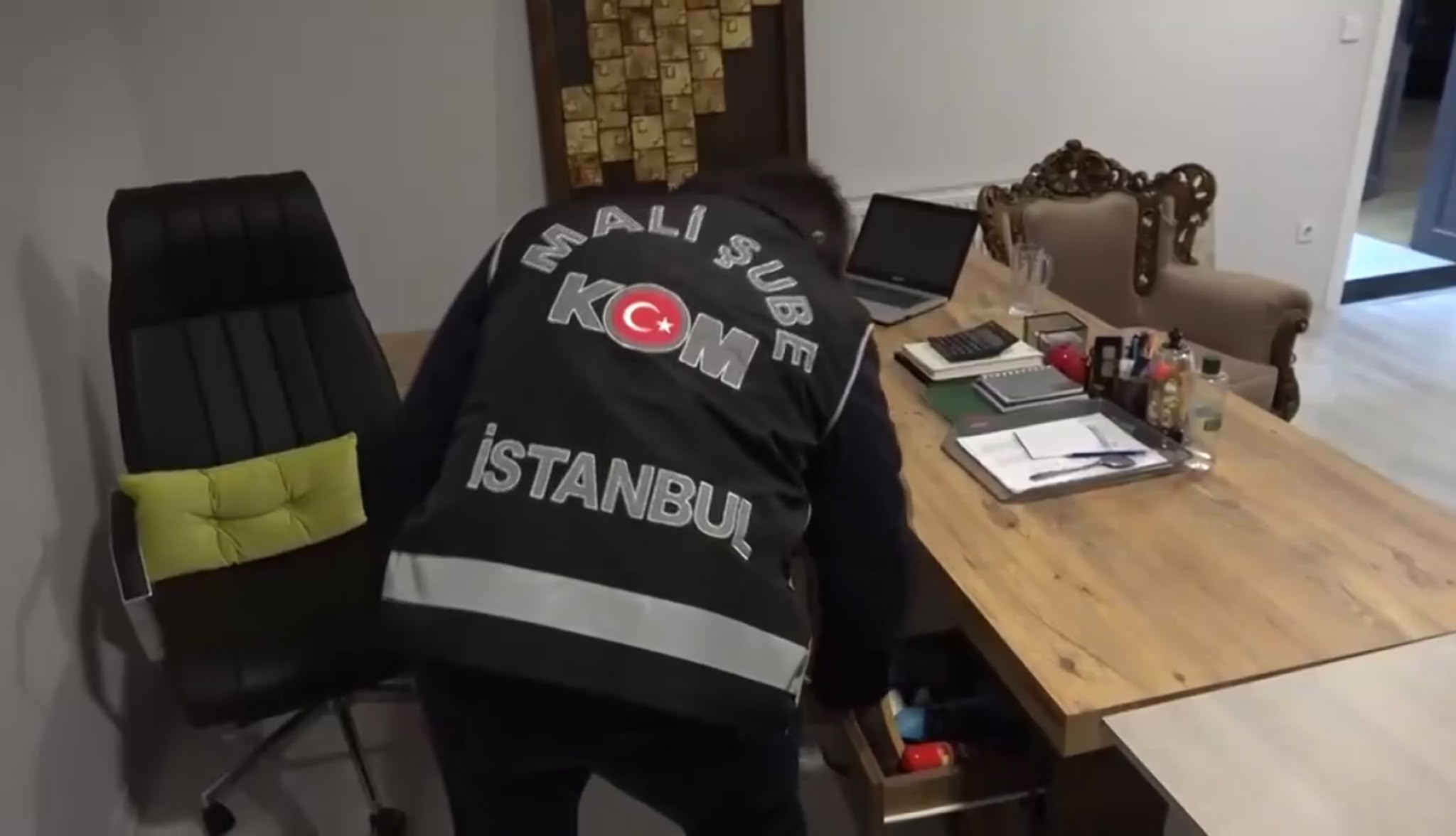 GÖVDE 1 — Mali Şube KOM İstanbul yelekli polis firma ofisinde masa ve çekmeceleri arıyor, temiz kare, 2048x1176