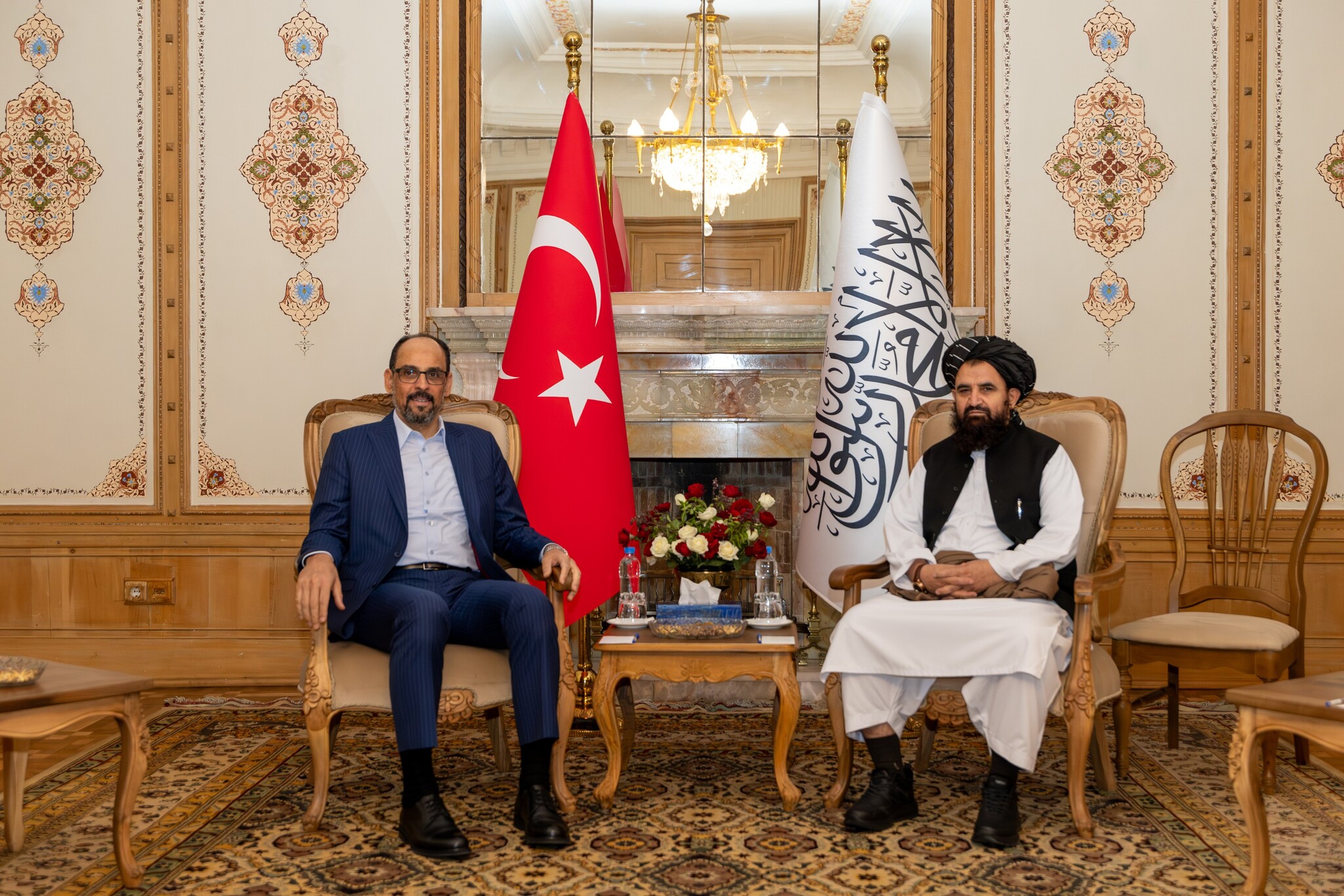 Kalın, Türk bayrağı ve Afganistan İslam Emirliği bayrağı önünde Afgan yetkiliyle görüşme salonunda