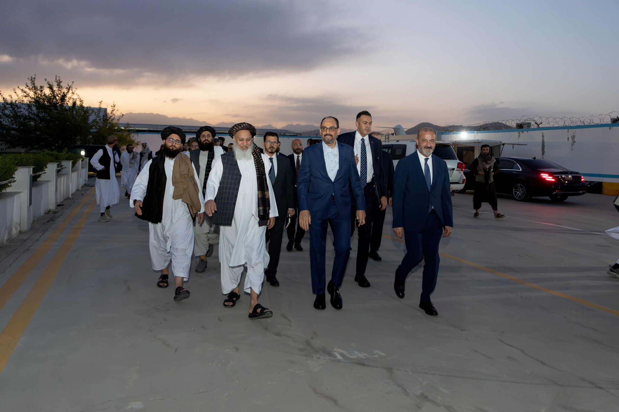 Kalın ve heyeti, havalimanı apronunda Taliban yetkilileriyle yürürken (gün batımı)