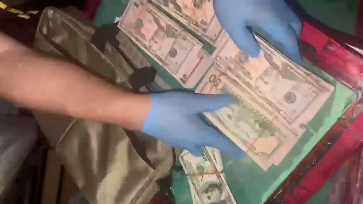 1280x720, aramada eldivenli ellerle çantadan çıkarılan sahte dolar desteleri. Logosuz, gövde fotosu.