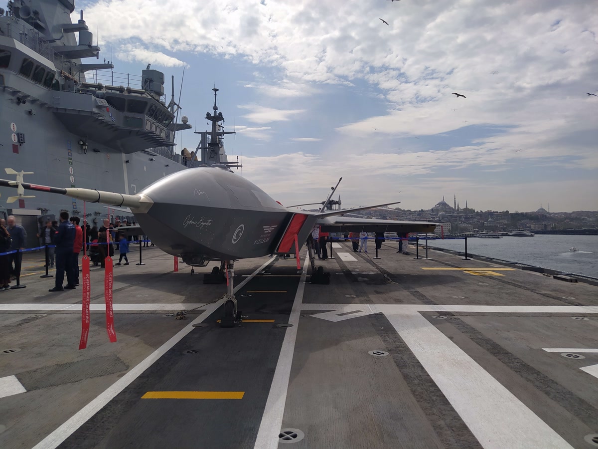 KIZILELMA prototipi TCG Anadolu'nun uçuş güvertesinde, yandan görünüm, arkada geminin ada yapısı ve ziyaretçiler. 8000x6000, çok yüksek çözünürlük. Lisans CC BY-SA 4.0.