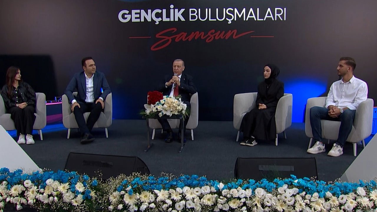 GÖVDE 1 — Sahnenin geniş planı: 'Gençlik Buluşmaları Samsun' fonu önünde Erdoğan ve soru soran dört genç koltuklarda; 12