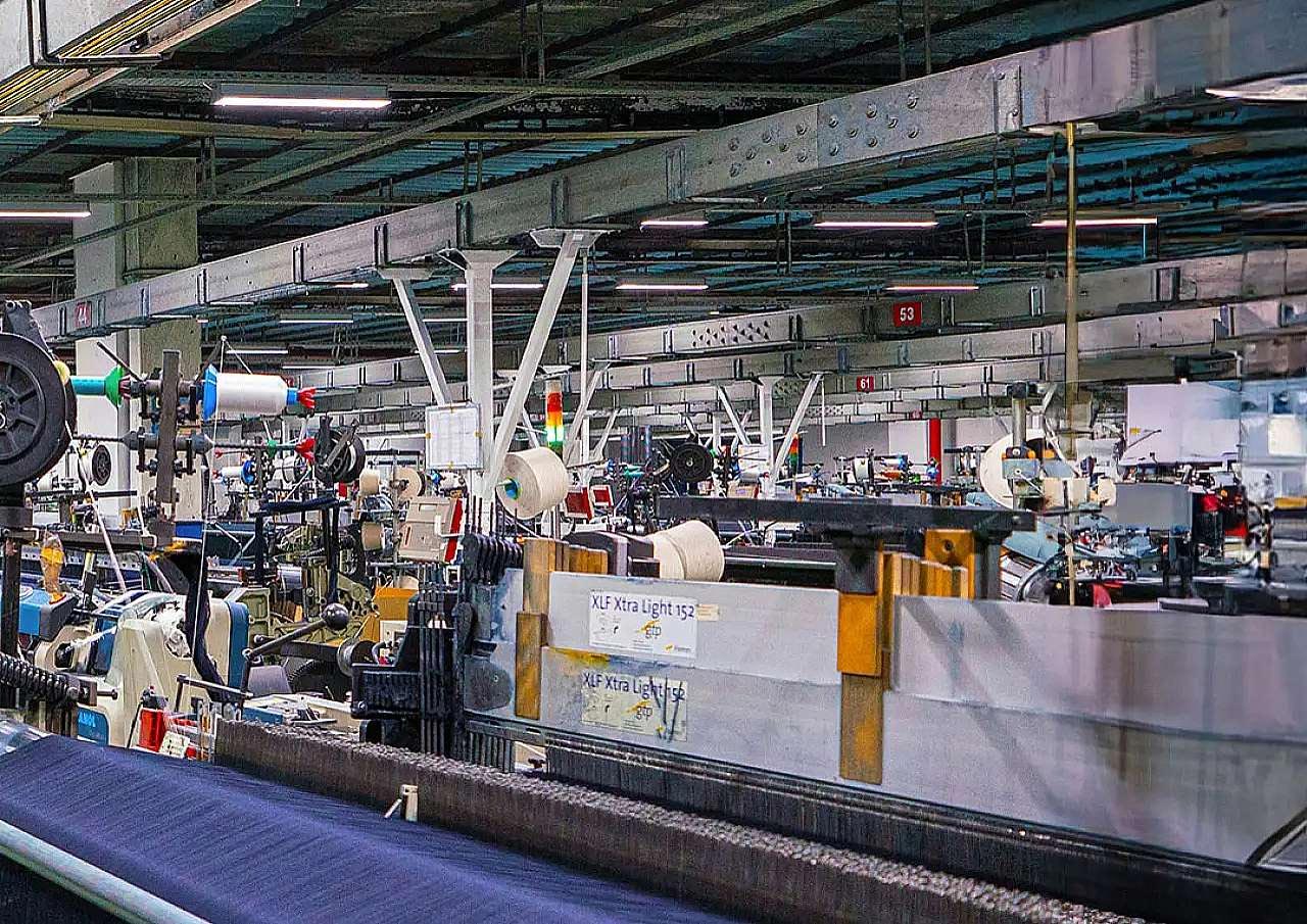 GÖVDE — Fabrikanın dokuma salonu, sıra sıra dokuma tezgâhları ve mavi denim kumaş; 1280x905, temiz