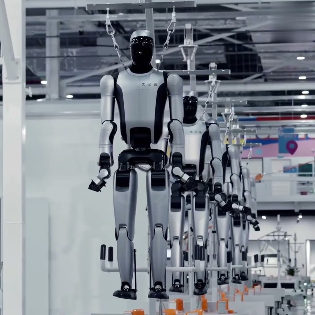 Üretim hattında askıda ilerleyen insansı robot gövdeleri