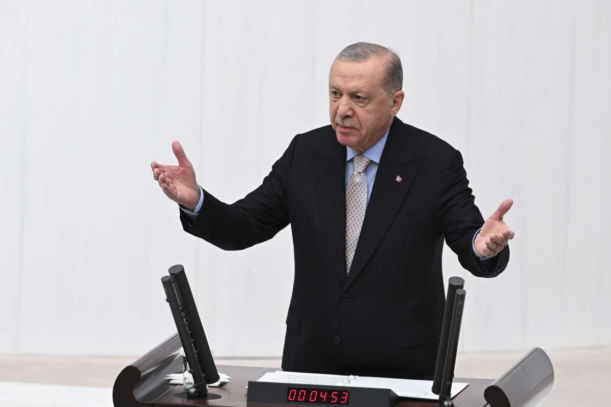 Cumhurbaşkanı Erdoğan Genel Kurul kürsüsünde, iki kolu açık, beyaz zeminli temiz kare (1500x1000; kürsü saati görünüyor, arşiv karesi olabilir). Kapak için ilk tercih.