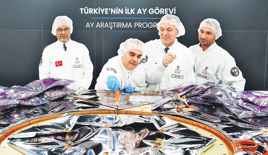 GÖVDE 2. Mühendisler aracın güneş paneli/yapı parçası üzerinde çalışırken; 931x539; arka fondaki 'Türkiye'nin İlk Ay Gör