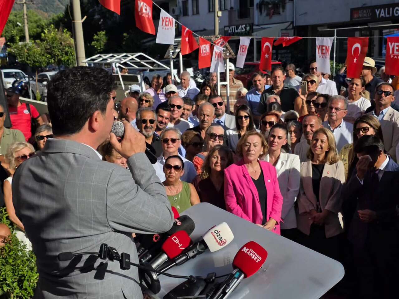GÖVDE 3 - Ünlü kürsüde kalabalığa konuşuyor, arkada Yeni Parti flamaları (kürsüde küçük mikrofon logoları var, kapağa de