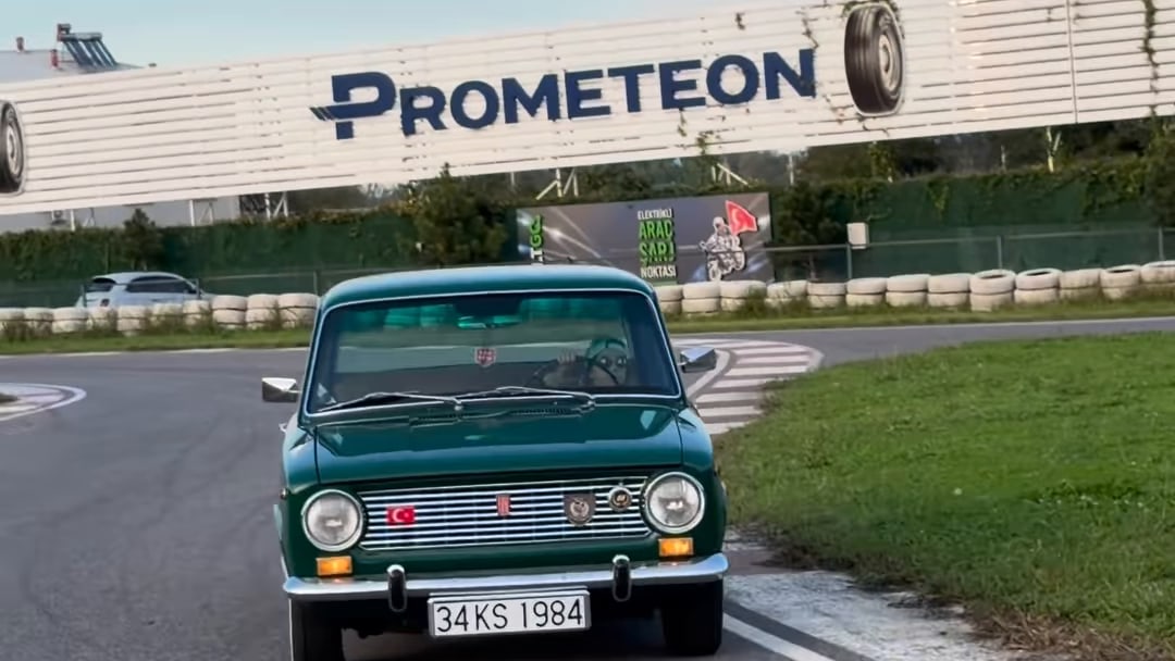 Klasik otomobil, yarış pistinde reklam panolarının önünden geçiyor